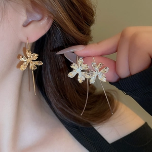 Detail of elegant gold iris flower drop earrings showing metal texture on a model
