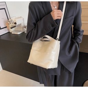 Close-up of cream tote bag featuring textured soft leather and protective metal feet