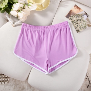 Detail of light purple yoga shorts with white trim placed on a soft white sofa background