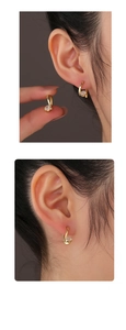 Detail view of gold S925 silver earrings with sparkling round zircon in elegant twist design