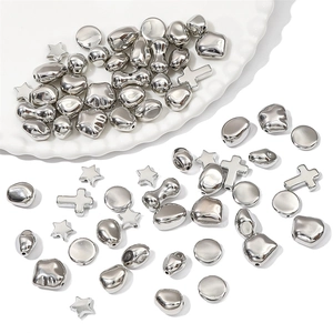 Silver star and cross metal beads for DIY jewelry making on white ceramic dish