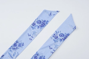 Detailansicht von hellblauem Stoff mit Blumenmuster, Schmetterlingsdruck und Schrägschnitt