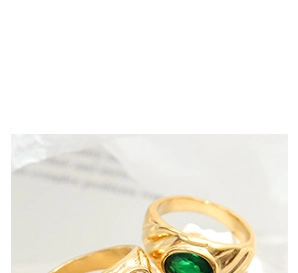 Macro-opname van vergulde ring met een ovale groene edelsteen en getextureerde band