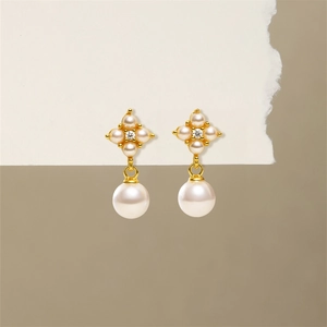 Close-up of S925 silver pearl drop earrings with flower shape and golden metal finish