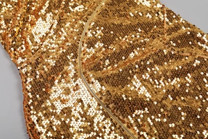 Détail des paillettes dorées et de la fermeture éclair métallique sur une robe de soirée