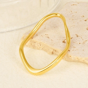 Irregular gold wave bangle in 304 stainless steel displayed on minimalist stone base