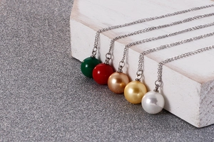 Vue détaillée de colliers de perles en vert, rouge, or et blanc sur support en bois