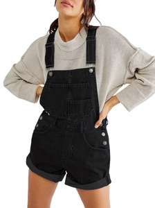 Detail shot of black denim overalls with multiple pockets and a beige knit sweater