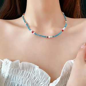 Detail shot of a beaded necklace with small blue pearls and colorful stones on a neck