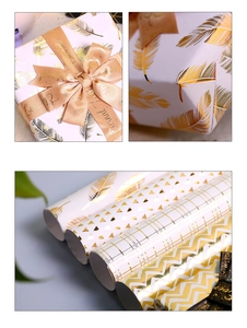Detail of gold foil gift wrap with feather patterns and elegant satin ribbons