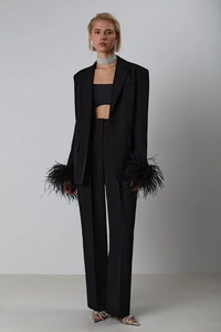 Close-up of black blazer cuffs with elegant feather trim and premium fabric texture