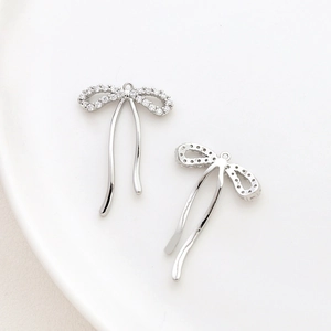 Detailed view of silver bow pendant with cubic zirconia and metal tassels for jewelry making