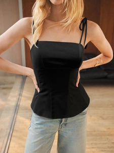 Detail of slim fit black tank top with delicate tie straps and soft lighting