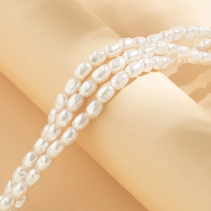 Macro detail of triple-strand rice pearl necklace with white iridescent luster on display