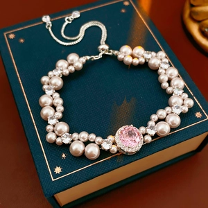 Close-up of pearl and zircon bracelet with pink gemstone on green velvet box