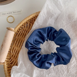 Detail of dark blue satin scrunchie with silky luster on rustic decorative background