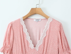 Detailed view of pink polka dot dress with V-neck lace trim and ruffled collar texture