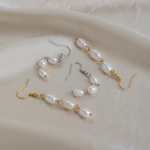 Elegant 18K gold and silver plated freshwater pearl drop earrings on beige silk fabric