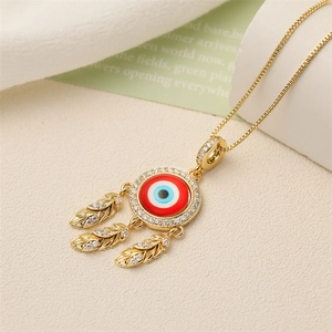 Dettaglio di una collana acchiappasogni dorata con pendente malocchio e piume di zircone