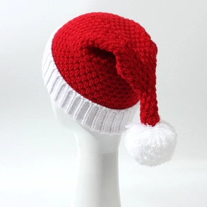Close-up of a red knitted Christmas hat with a thick white yarn pom-pom and clear texture