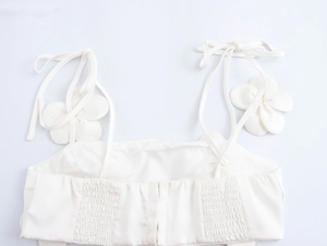 Detail view of the white crop top featuring 3D floral accents and elastic waistband