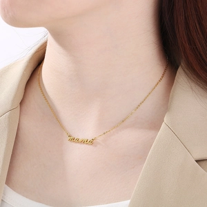 Detail of 18K gold plated mama cursive pendant necklace worn with a chic beige blazer