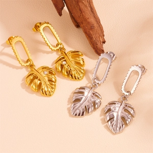 Elegante goldene und silberne Blattohrringe mit funkelnden Kristallen auf strukturierter Fläche