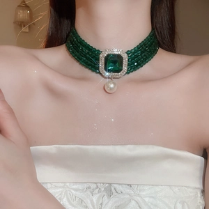 Macro shot of vintage emerald choker featuring multi-layer green beads and pearl pendant