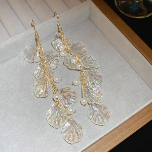 Detail of elegant gold drop earrings with iridescent shell leaves and white pearls