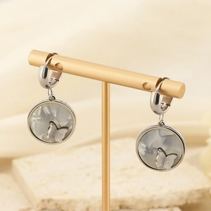 Detail of silver drop earrings with shell inlay and matte butterfly on a stone base