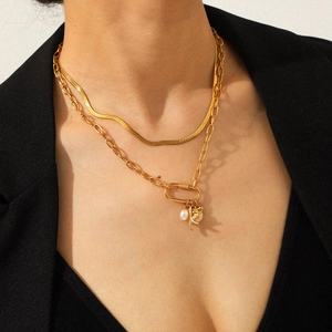 Detalle de un collar de capas en acero inoxidable de 18K con perla y hojas doradas