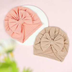 Close-up of pink and beige ribbed baby hats featuring large decorative bow details