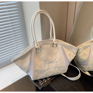 Detail of cream bowling bag with blue embroidery and mesh side panels in natural light
