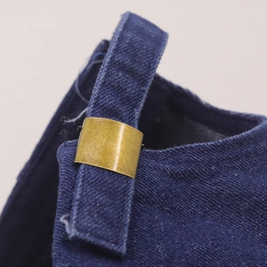 Dettaglio macro della fibbia in metallo vintage e cuciture su cappellino in denim blu