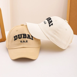 Detail of DUBAI embroidery on khaki and beige cotton baseball caps for children