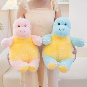 Detailed close-up of soft blue and pink dinosaur plush toys held in a cozy home setting