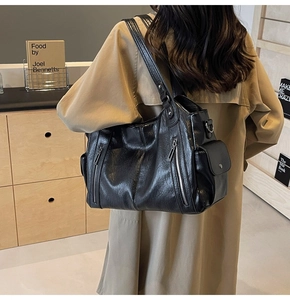 Detail view of large black faux leather tote bag with silver zippers and side pockets