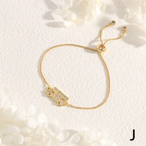 Close-up of golden adjustable bracelet featuring a school bus charm with white zircons