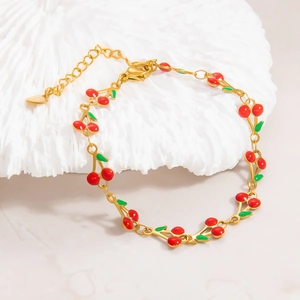 Detailed close-up of 18k gold-plated cherry bracelet with green enamel and lobster clasp