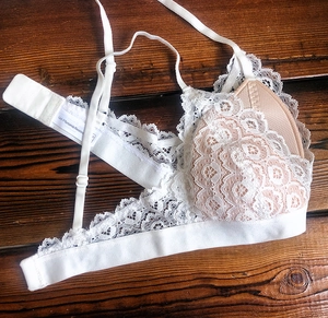 Détail d'un soutien-gorge en dentelle blanche avec doublure chair sur fond bois