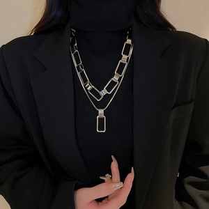 Detailed view of layered silver metal chain necklace and hollow rectangular pendant