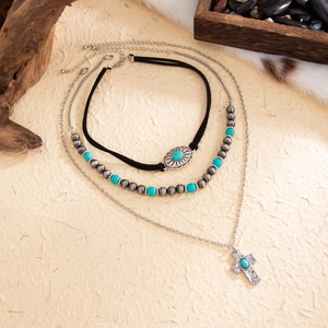 Detail of bohemian layered necklace with turquoise beads and silver cross pendant