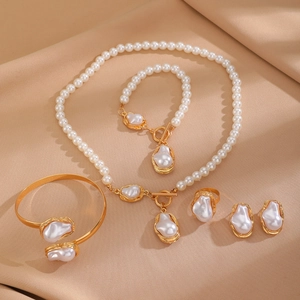 Flat lay of baroque pearl jewelry set featuring golden metal necklace and earrings