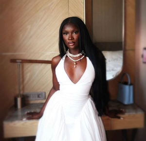 Detail of white deep V-neck halter dress with layered pearl necklaces on a model