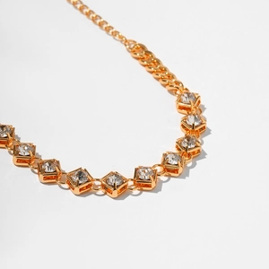 Gold plated bracelet with square zircon stones and claw setting on a white background