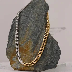 Detailed close-up of two-tone stainless steel Cuban link necklace on grey stone
