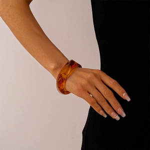 Close-up of translucent amber acrylic cuff bracelet worn on wrist for retro style
