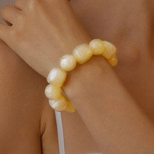 Close-up of yellow acrylic beaded bracelet with cat eye effect on a woman wrist
