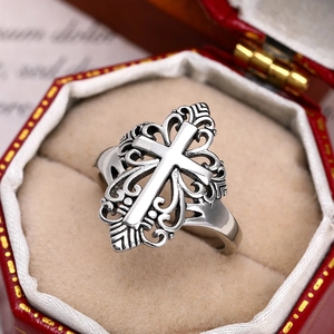 Macro detail of gothic hollow cross ring with intricate floral carvings in a red jewelry box