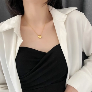 Polished golden heart pendant necklace worn on a model with minimalist style